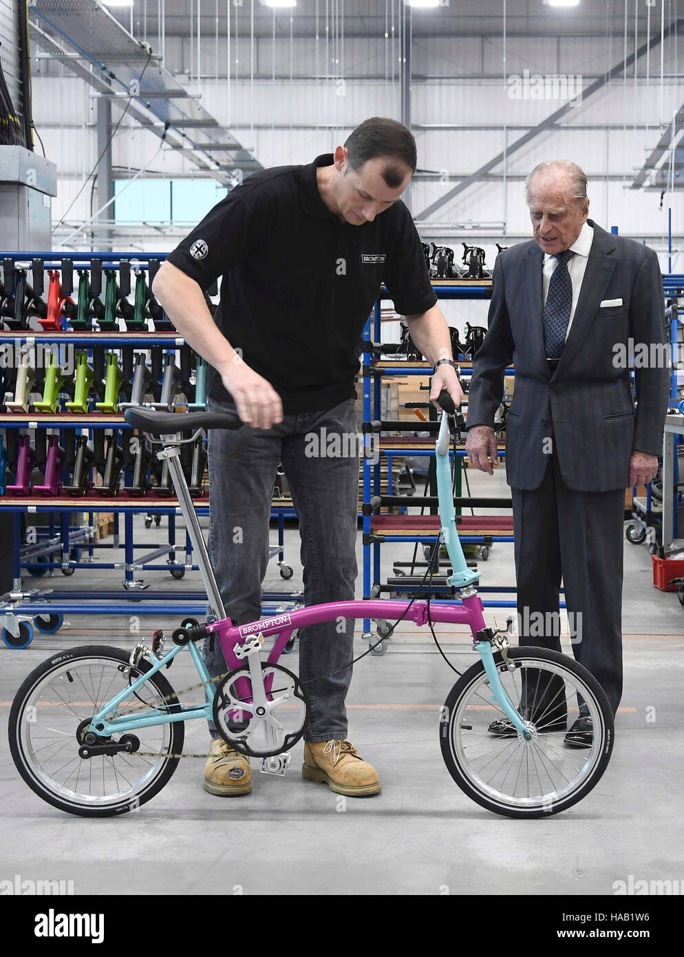 Der Herzog von Edinburgh wird ein Brompton Fahrrad durch die Firma CEO Will Butler-Adams als er seine neue Fabrik in Greenford, London öffnet angezeigt. Stockfoto