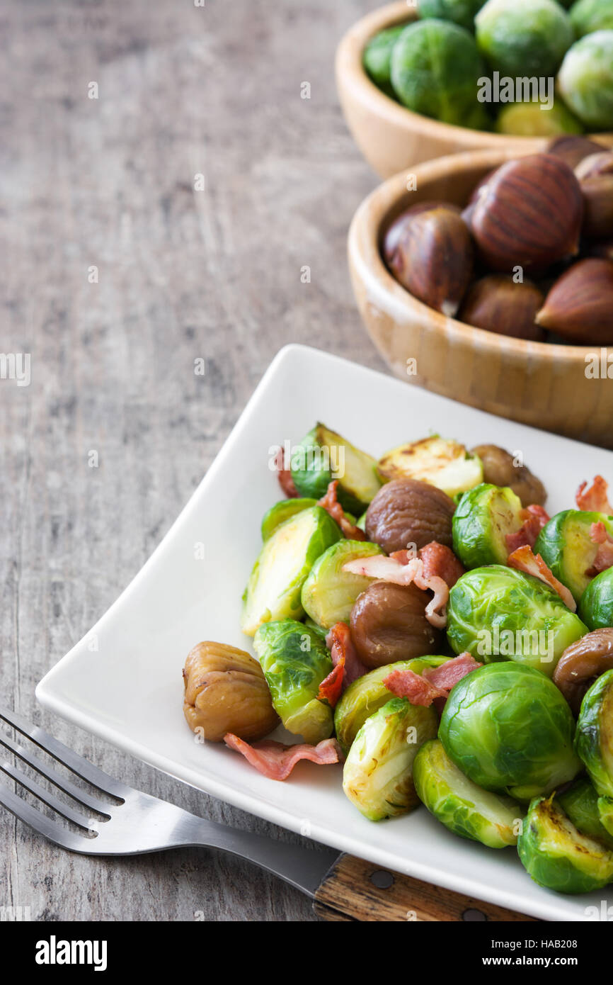 Rosenkohl mit Kastanien und Speck auf Holztisch Stockfoto