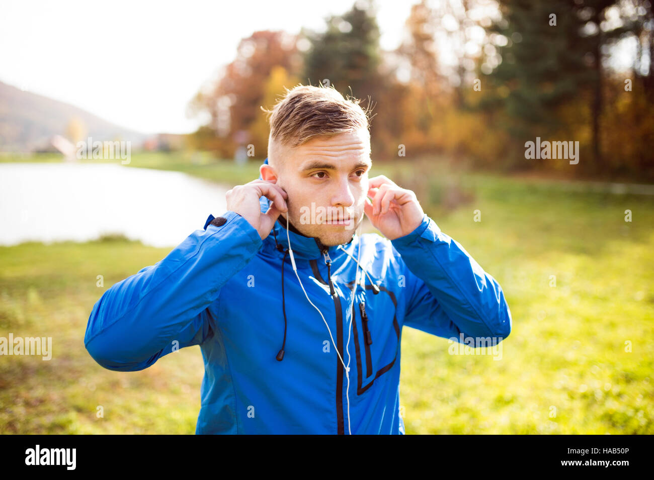 Junge Läufer mit Kopfhörer außerhalb im sonnigen Herbst Natur Stockfoto