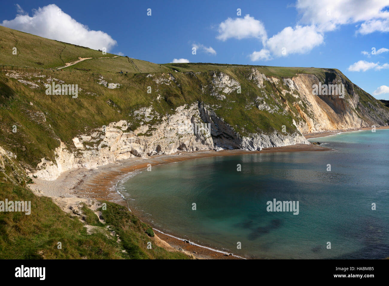 St. Oswald Bay und Mann o Krieg Felsen helle Wolken im blauen Himmel und Cliff Spiegelungen im Wasser - Dorset UK Stockfoto