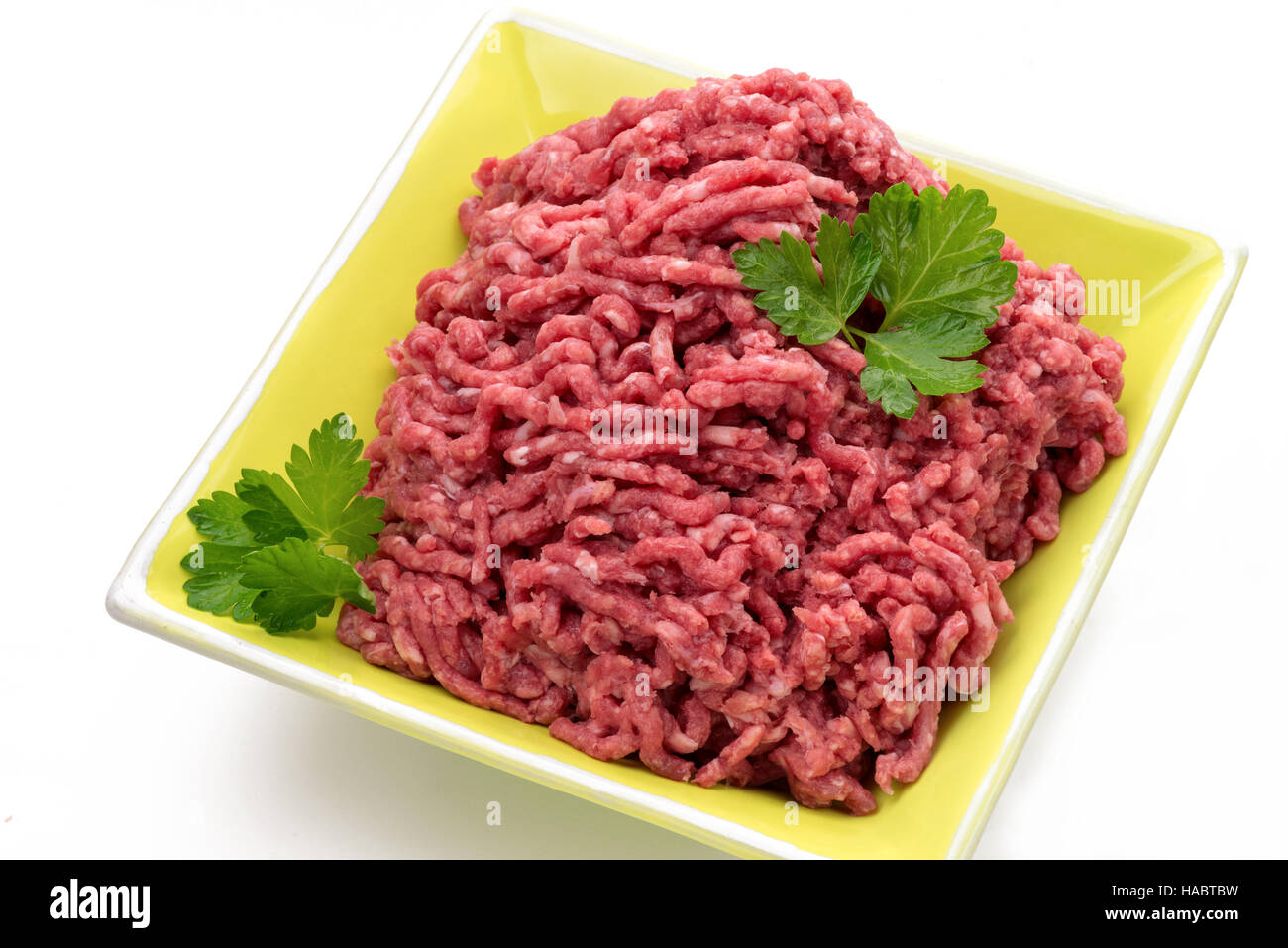 Rohes Rindfleisch Hackfleisch mit Beilage in einem bunten Teller auf weißem Hintergrund Stockfoto