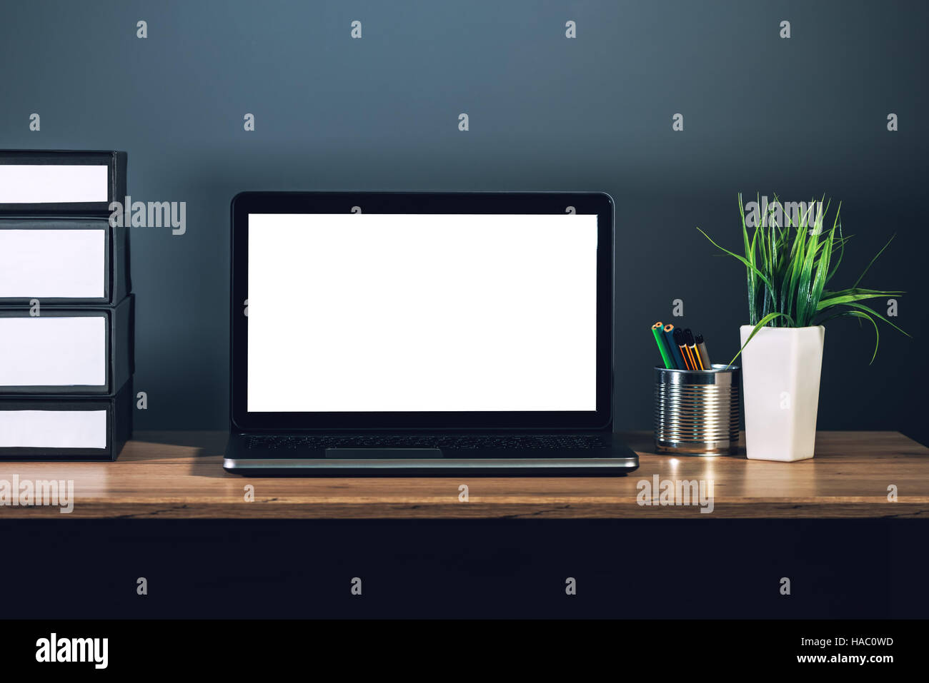 Laptop-Computer mit leeren Bildschirm als textfreiraum auf Büro-Desktop im dunklen Innenraum platziert Stockfoto