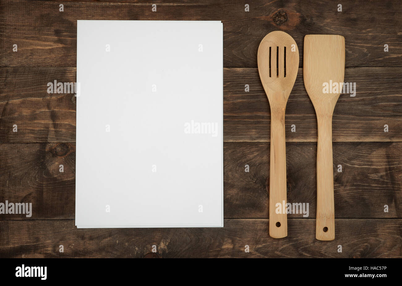 Hölzerne Küchenutensilien und leere Papierbögen für Rezepte auf Holzplatte Stockfoto
