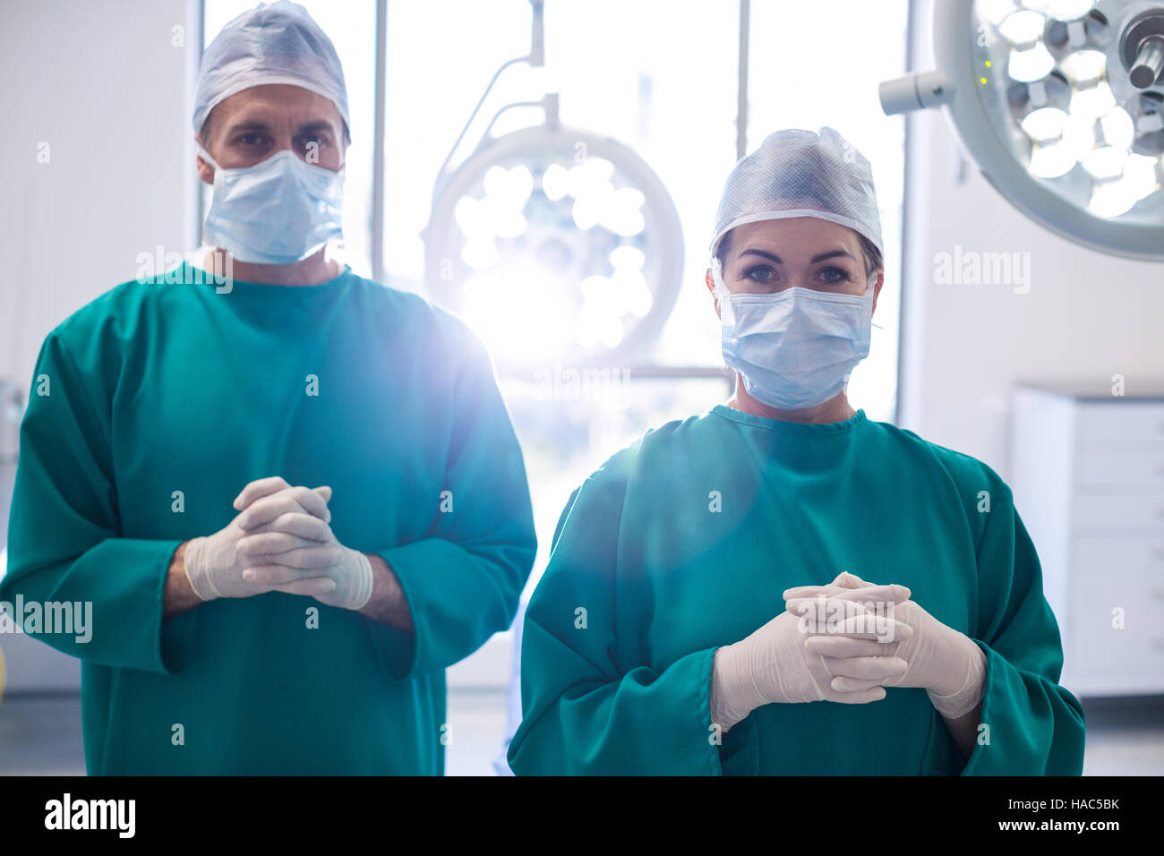 Porträt des Chirurgen stehend mit den Händen umklammert im OP-Saal Stockfoto