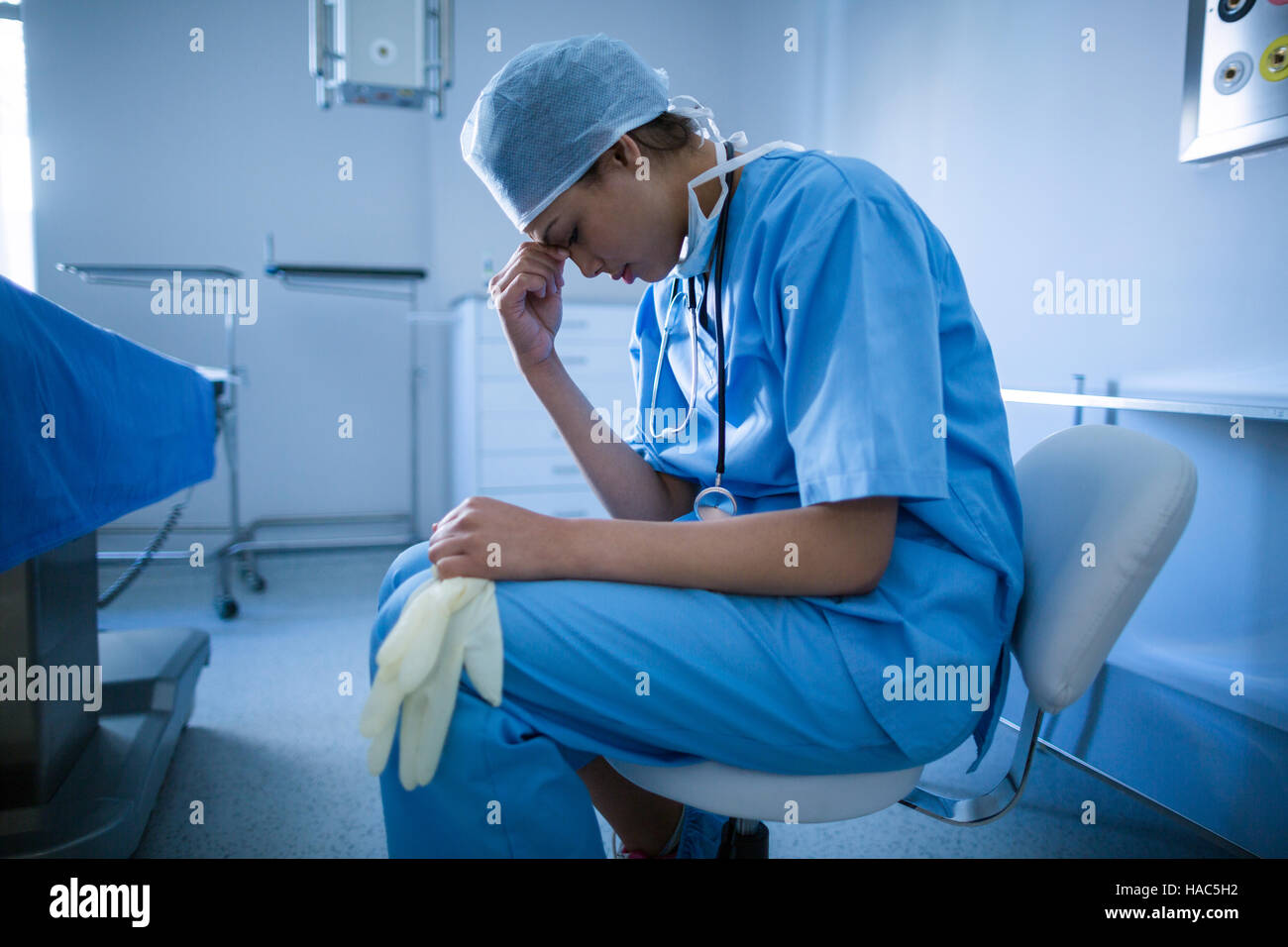 Depressive Chirurgen, die auf einem Stuhl sitzend Stockfoto