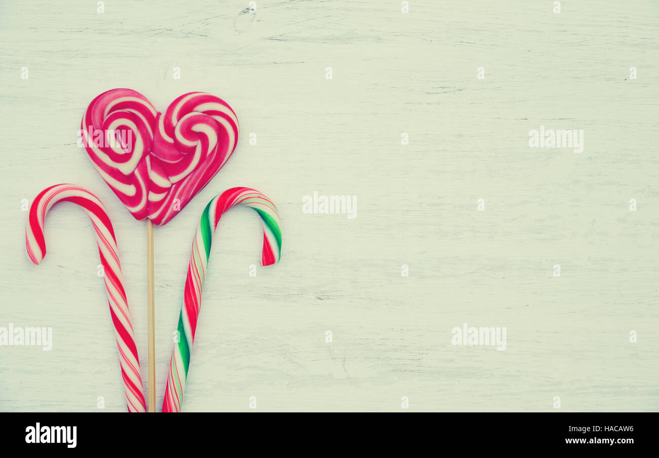 Lutscher in Form eines Herzens und Süßigkeiten auf einem hölzernen Hintergrund im Vintage-Stil. Platz für Text. Ansicht von oben Stockfoto