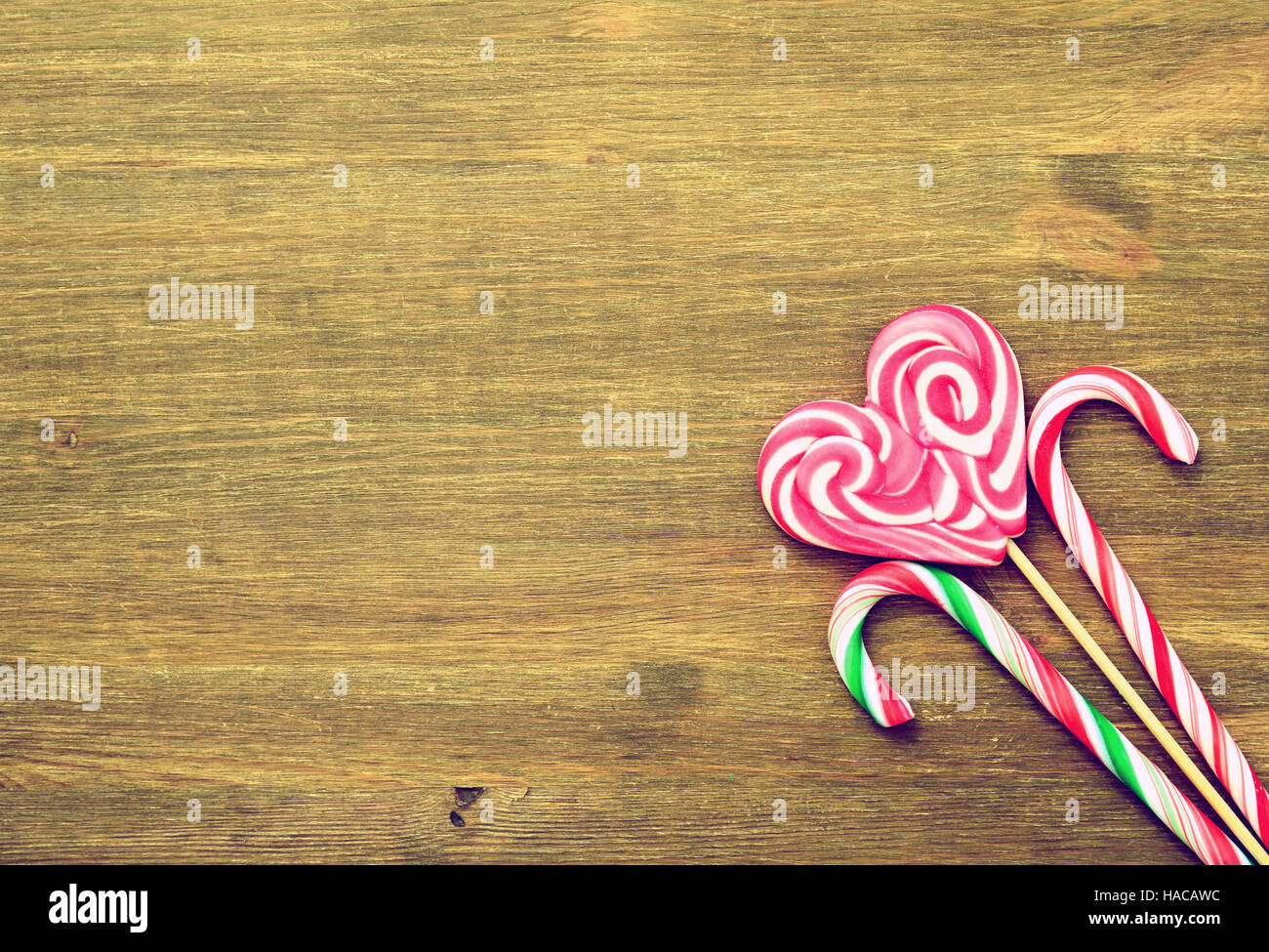 Lutscher in Form eines Herzens und Süßigkeiten auf einem hölzernen Hintergrund im Vintage-Stil. Platz für Text. Ansicht von oben Stockfoto