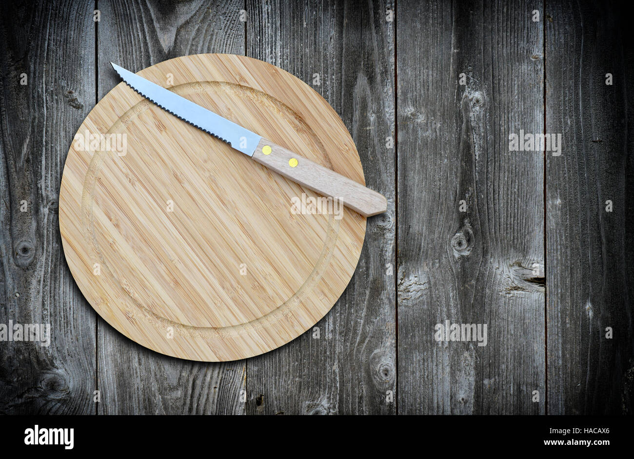 Leere Bambus Schneidbrett und Messer auf einem alten Holztisch für Warenpräsentation. Ansicht von oben Stockfoto