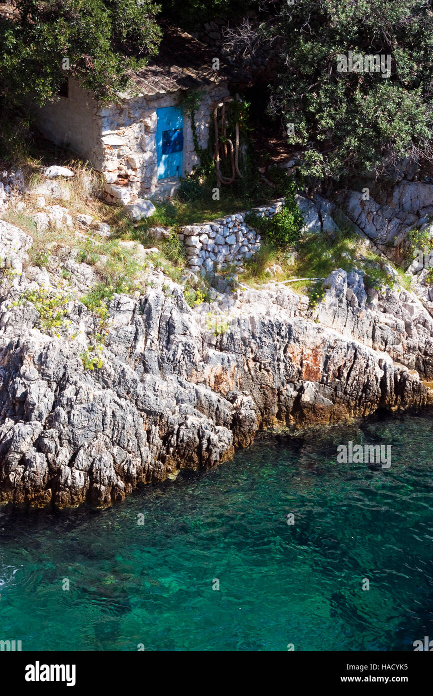 Kleines altes Steinhaus auf Klippe am tiefblauen Adria in Kroatien Stockfoto