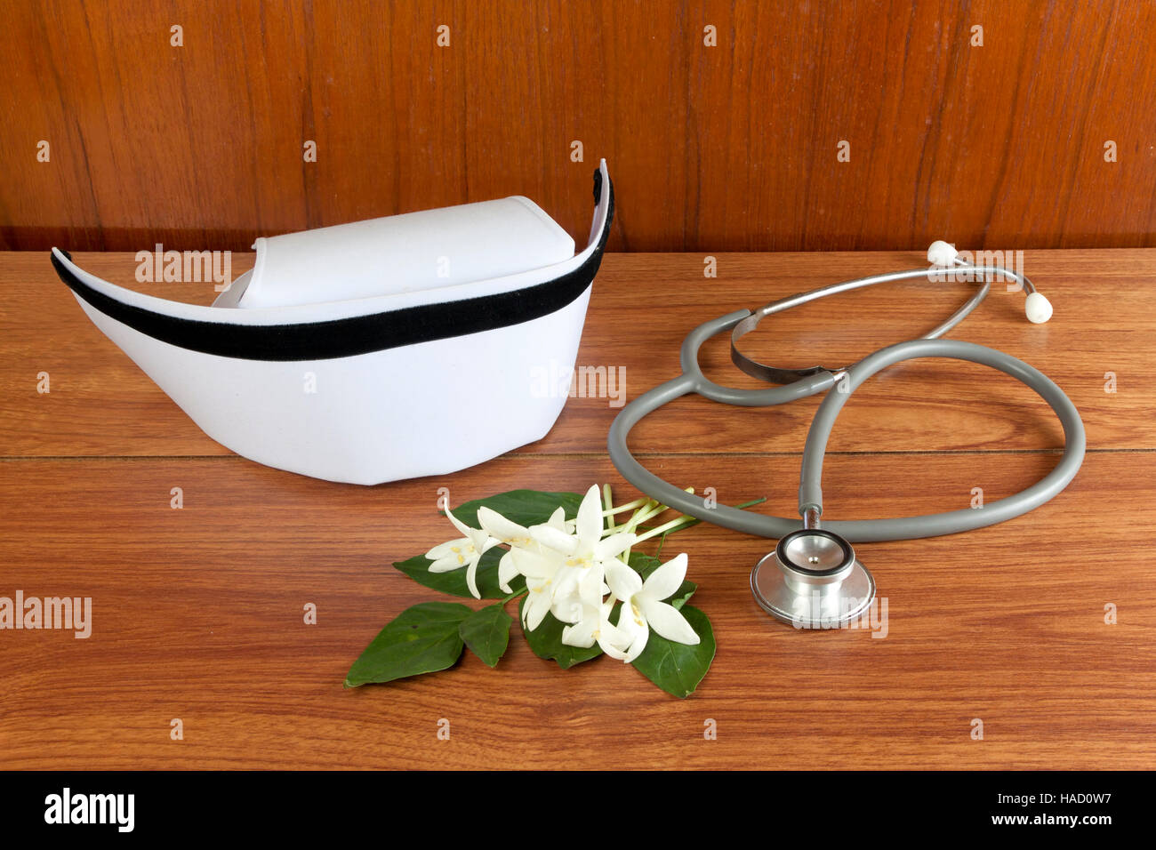 Weißer Hut Krankenschwester und Millingtonia Hortensis Blumen und Stethoskop auf Holztisch. Symbol für Thailand und Thai traditionelle Medizin Pflege. Stockfoto