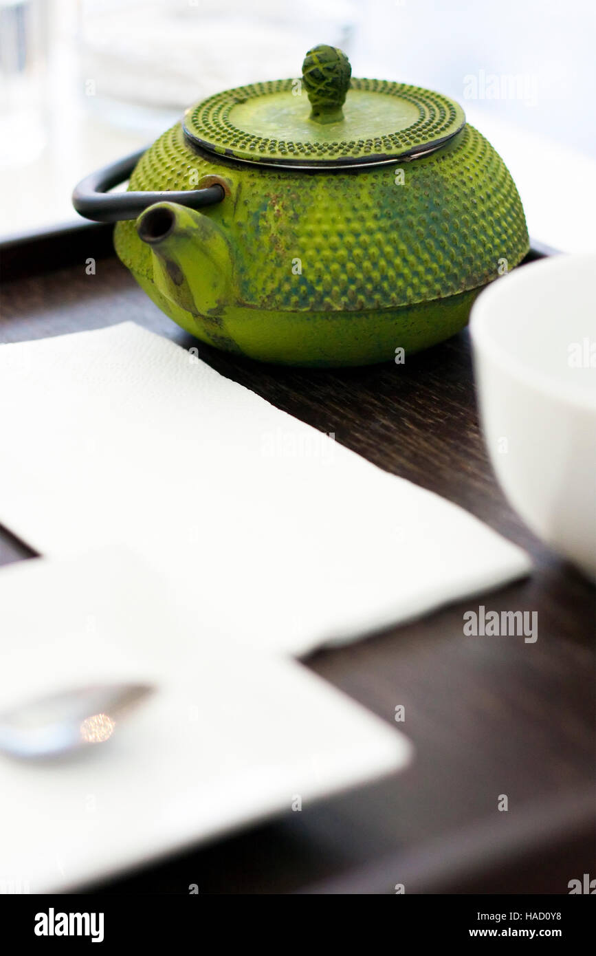 Grüne Teekanne auf Holztablett mit weißen Teetasse Stockfoto