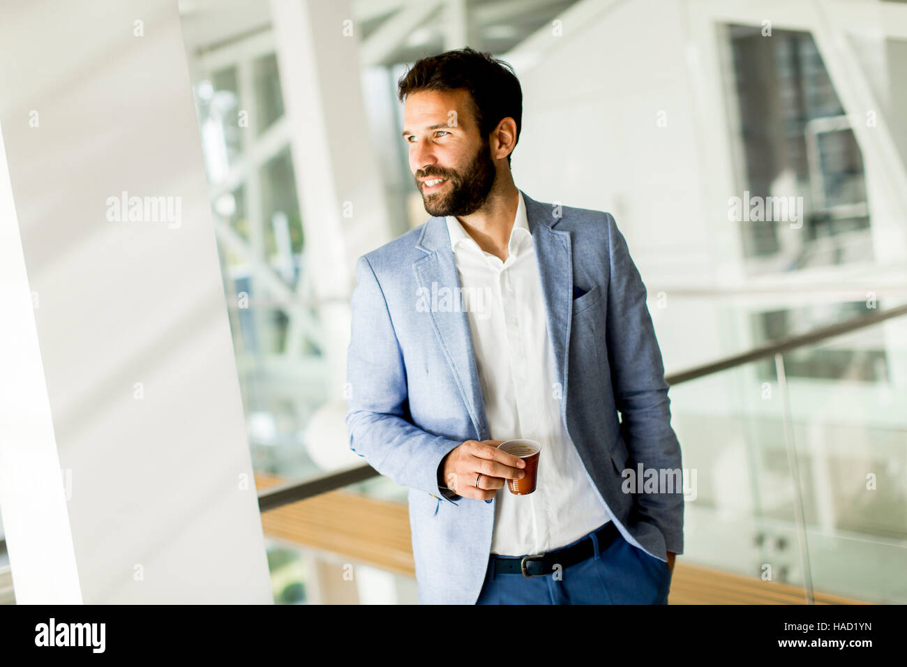 Geschäftsmann in einem Business-Anzug und eine Tasse Kaffee in einem Bürogebäude. Stockfoto