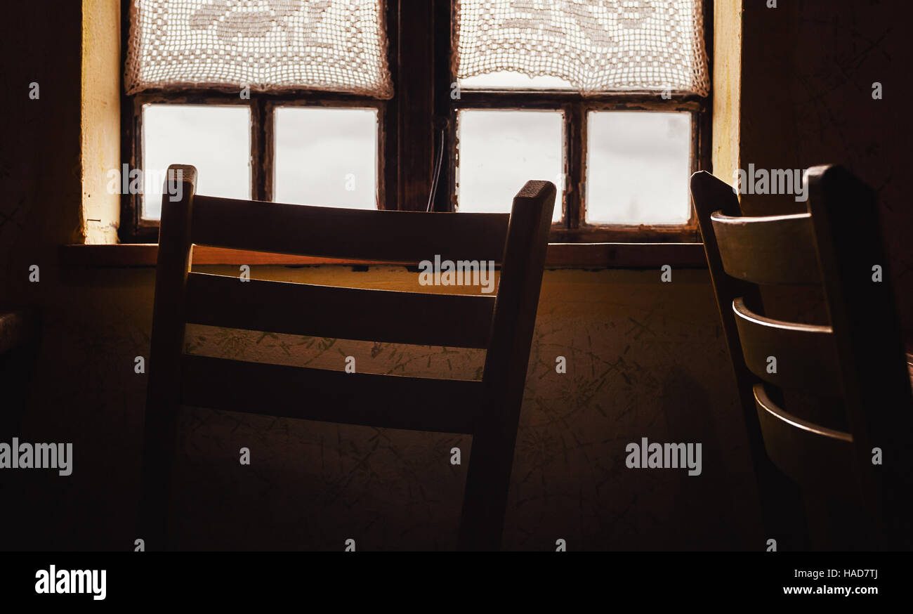 Detailansicht eines alten Holzfenster und Stuhl davor. Stockfoto