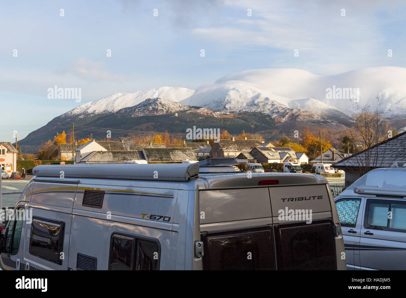 Wohnmobile und ein Schnee bedeckt Skiddaw reichen von den öffentlichen Fußweg neben der Scotgate Campingplatz, Braithwaite, Lake District Cumbria, UK Stockfoto