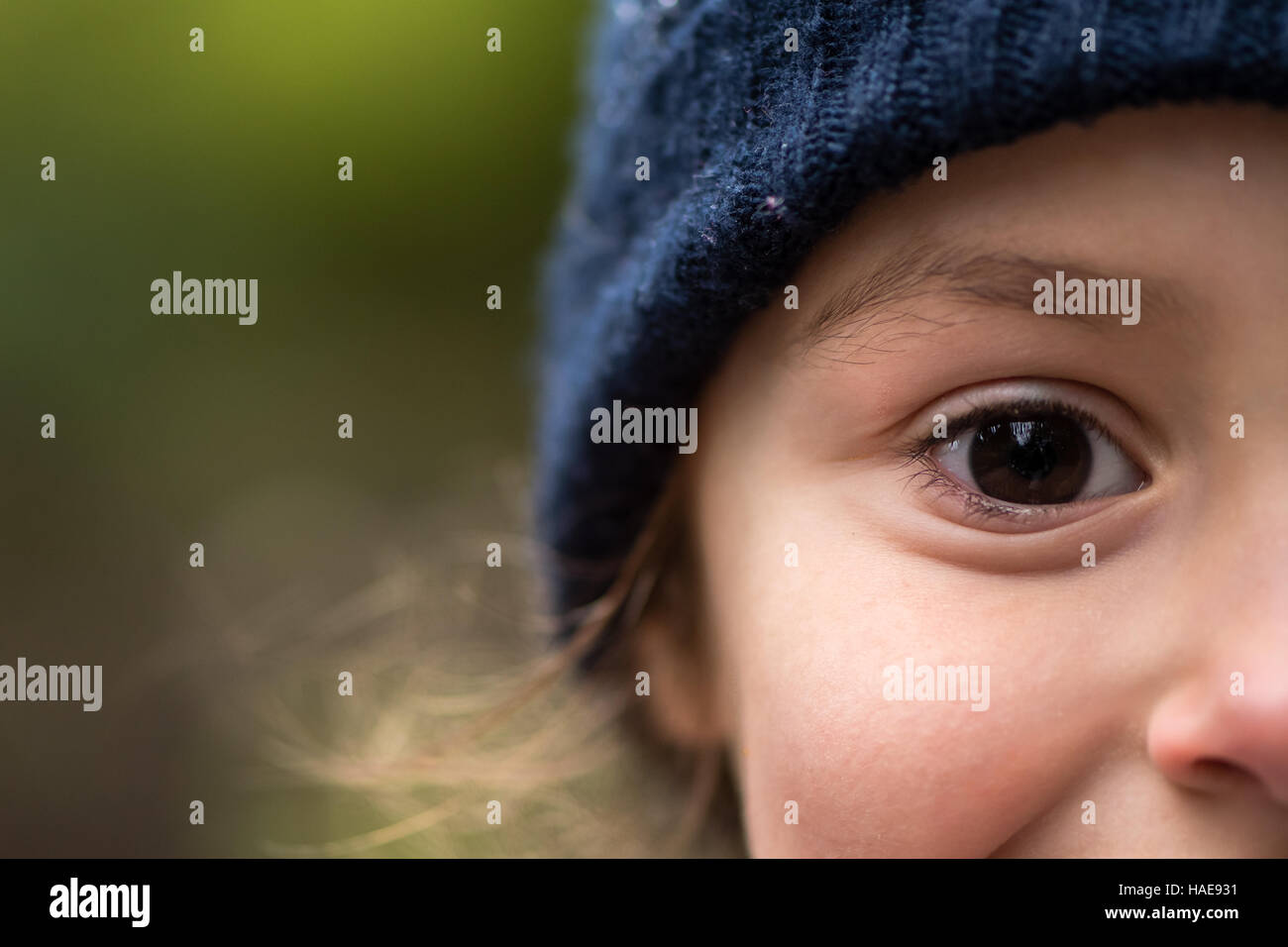 Junge Mädchen in warme blaue Wollmütze. Halbes Gesicht des Kindes in wolligen Wintermütze smily mit nur Auge vollständig im Rahmen Stockfoto