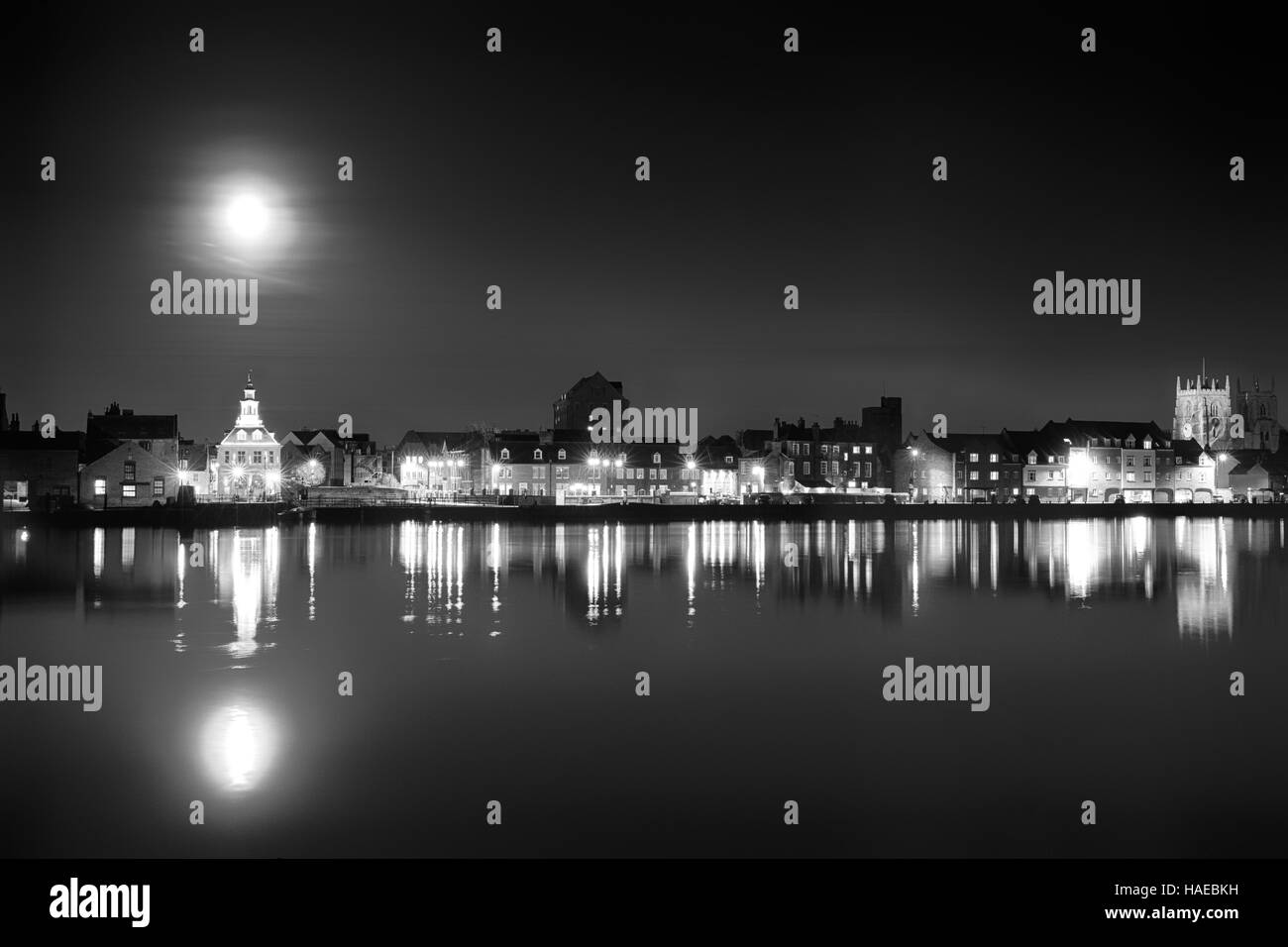 Supermoon steigt über dem Hafen von Kings Lynn in Norfolk UK. Schwarz / weiß Landschaft des Gebäudes, Nachtlichter und Wasserspiegelungen Stockfoto