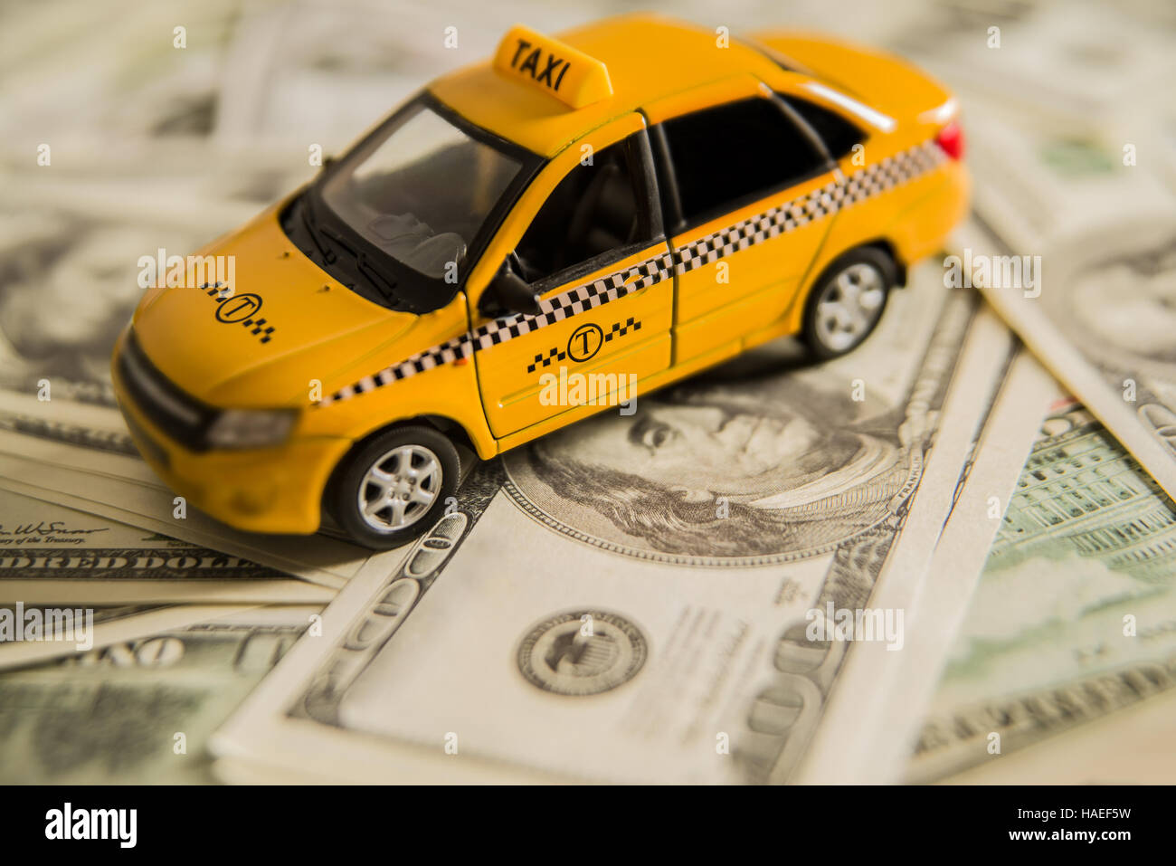 gelbes Taxi Auto auf Banknoten - 100 hundert stehen. Closeup. Spielzeugauto aus Metall. Stockfoto