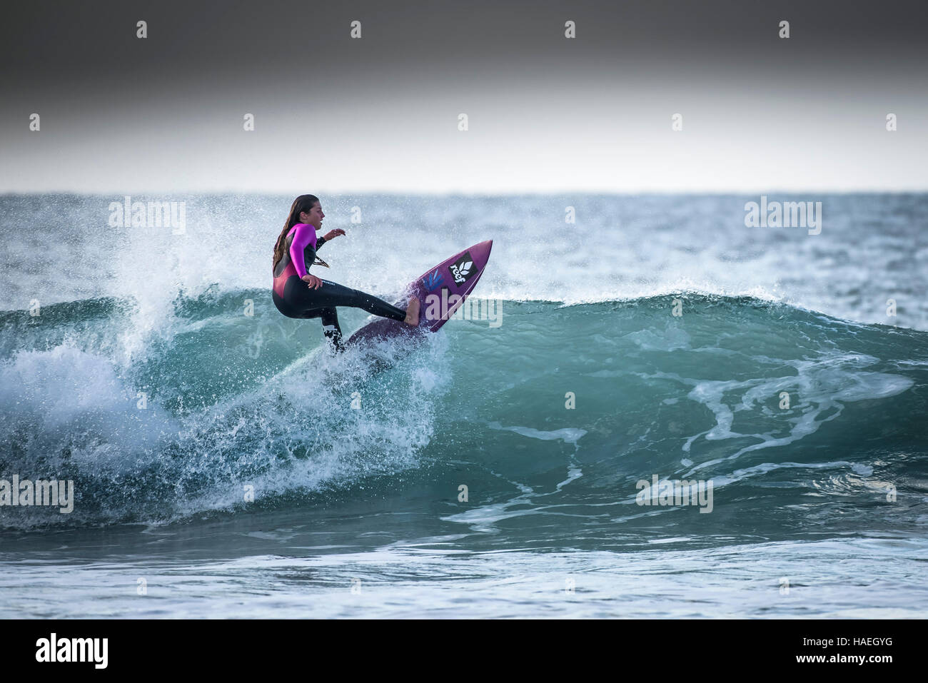 Eine weibliche Surfer reitet eine Welle an Fistral in Newquay, Cornwall. Großbritannien, England, UK. Stockfoto