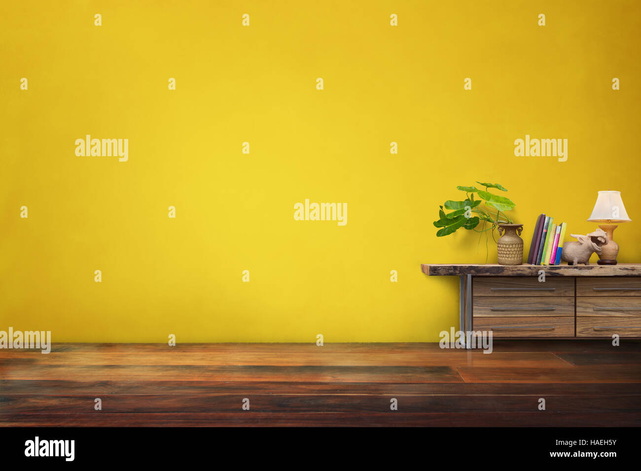 grüne Pflanzen Keramik Vase auf Schublade aus Holz in leere gelbe Vintage Wohnzimmer Interieur Stockfoto