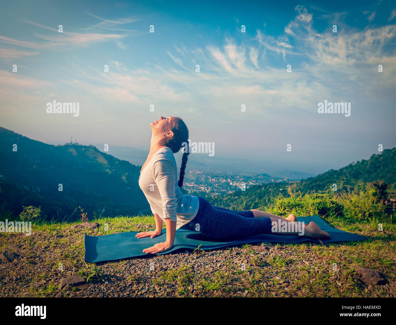 Yoga im freien - Frau praktiziert Ashtanga Vinyasa Yoga Surya Namaskar Sonnengruß Asana Urdhva Mukha Svanasana - mit Blick nach oben auf Hund-Pose in Berg Stockfoto