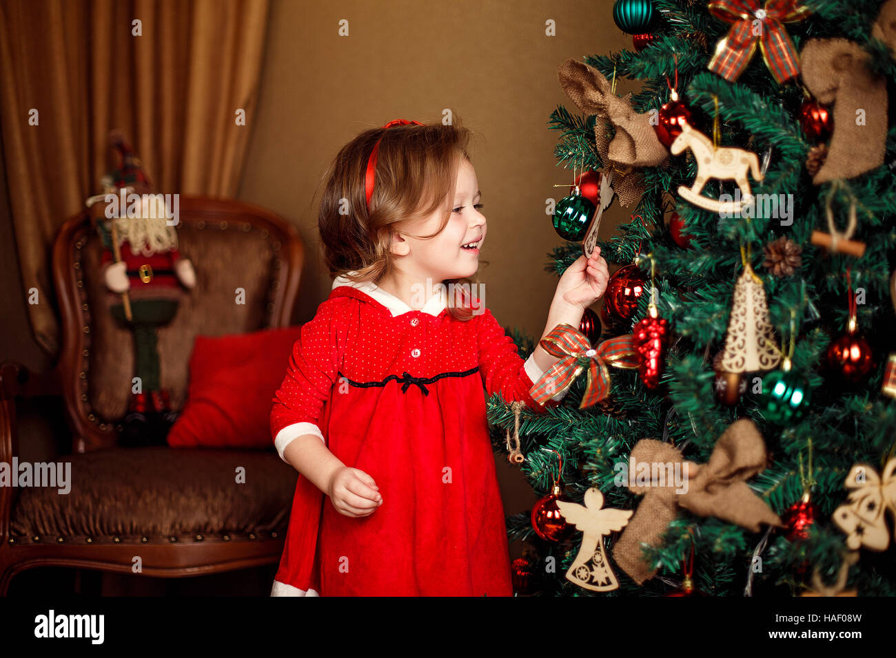 Stehen Mädchen stellt Dekoration zu einem Weihnachtsbaum. Vertikale ind Stockfoto
