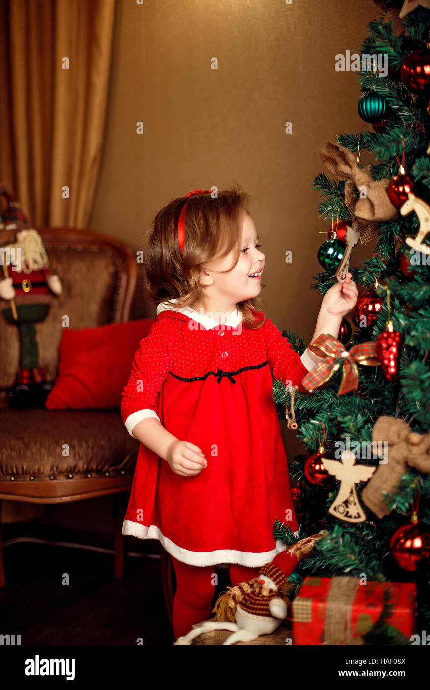 Stehen Mädchen stellt Dekoration zu einem Weihnachtsbaum. Vertikale ind Stockfoto