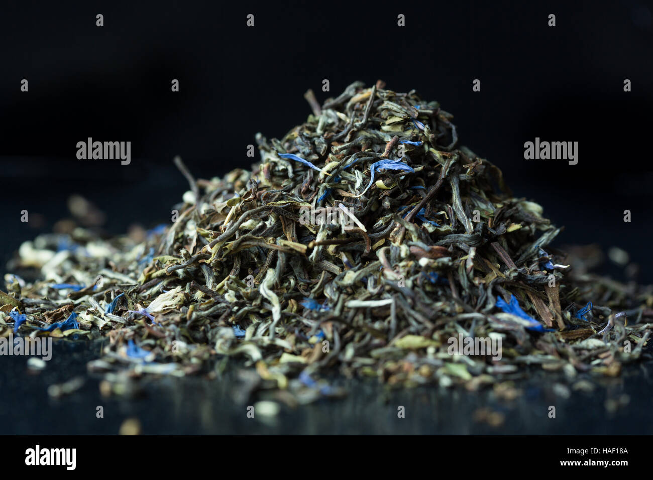 Haufen von grünem Tee Blätter mit blauen Blüten Stockfoto