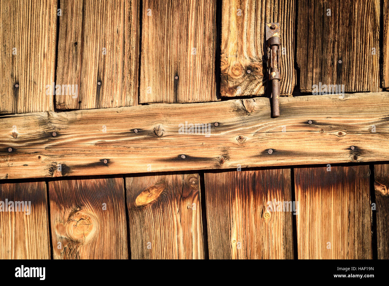 Rostiges Metall Scharnier auf Alter verblasst Holz in braun. Vertikale Zusammensetzung von Fading Holz und eine Türöffnung Eingang. Stockfoto