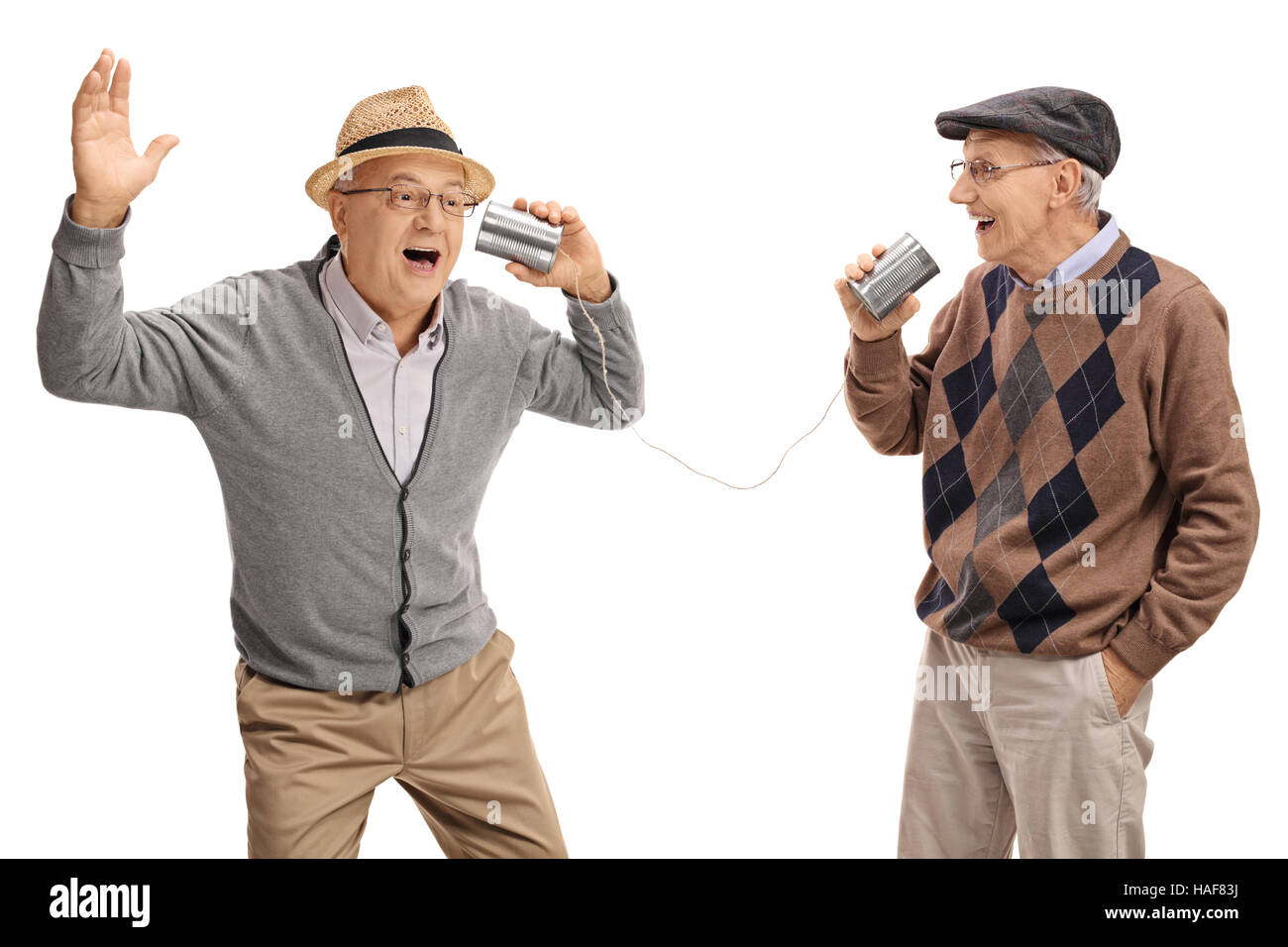 Fröhliche Senioren erzählen von Witzen miteinander durch eine Blechdose Telefon isoliert auf weißem Hintergrund Stockfoto