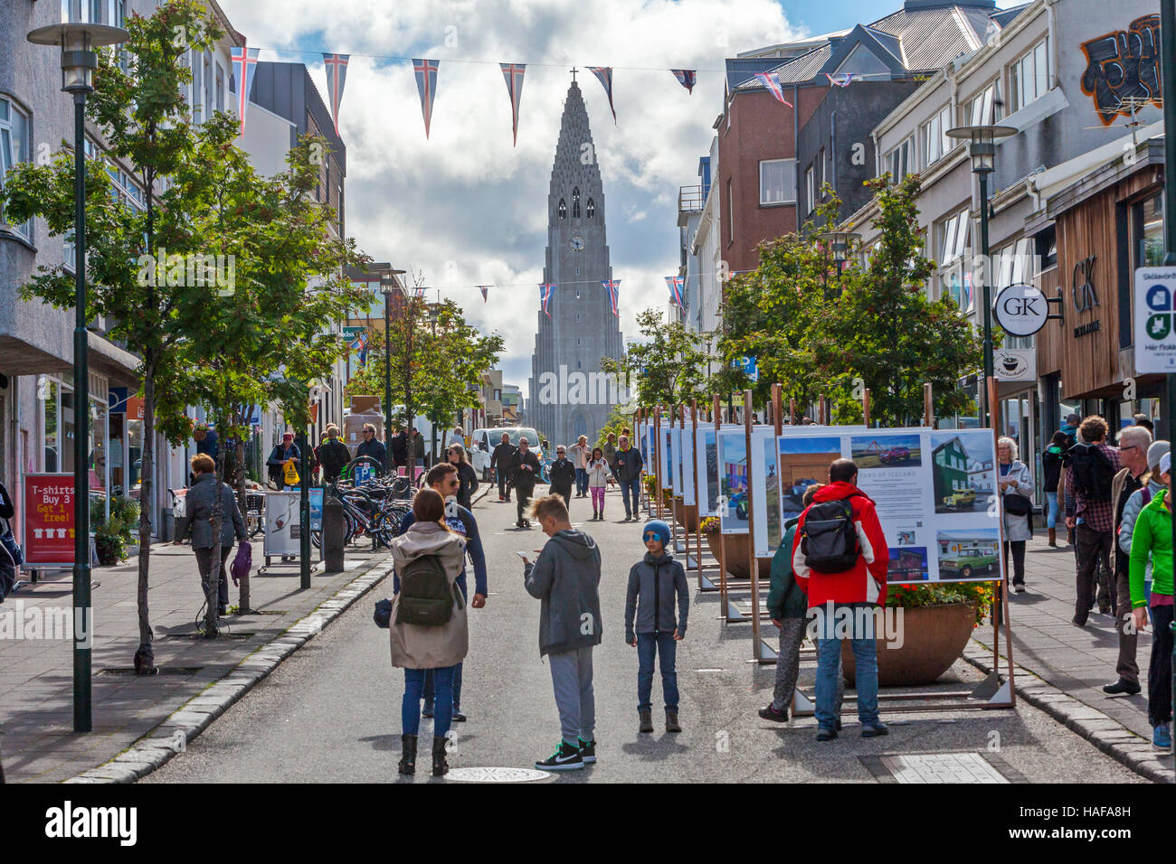 Menschen, Touristen zu Fuß in der Einkaufsstraße in Reykjavik, Island und der lutherischen Kirche Hallgrimskirkja wird gesehen. Stockfoto