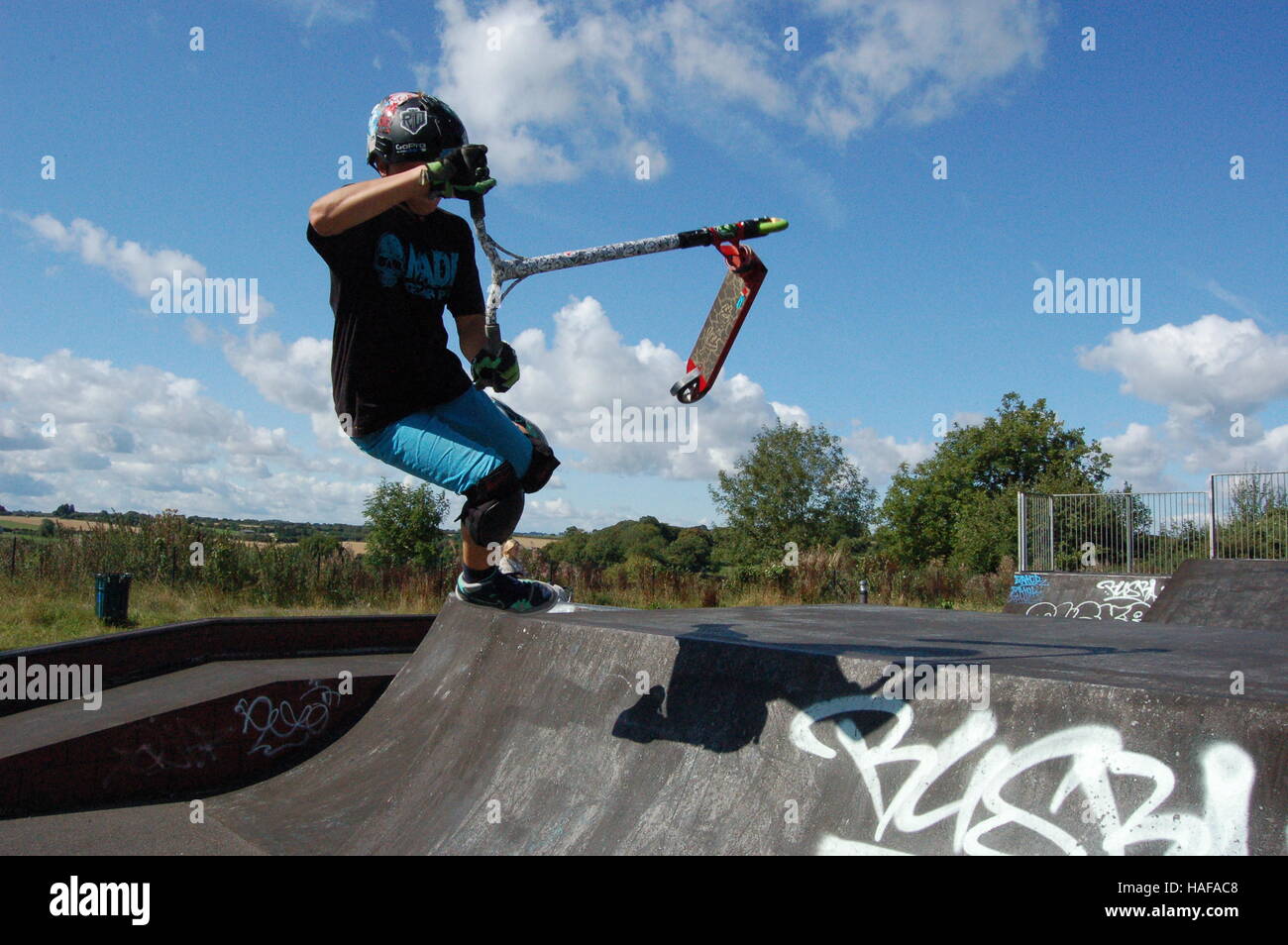 Scooter Barspin Trick über eine Rampe, Bad Stockfoto