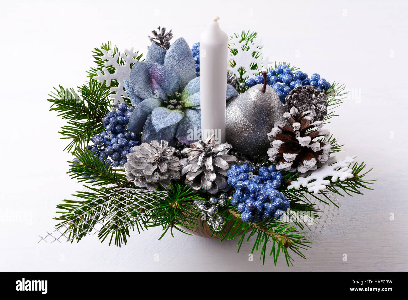 Weihnachten-Tafelaufsatz mit Kerze und blaue Seide Weihnachtssternen. Weihnachten Hintergrund mit dekorierten Tannenzapfen. Stockfoto