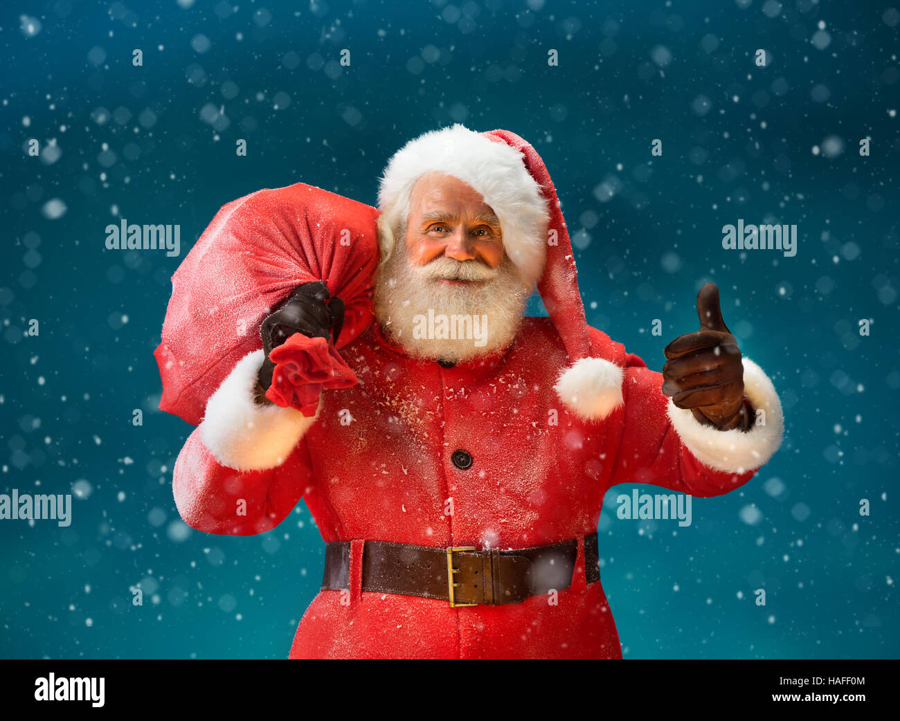Happy Santa Claus gestikulieren Daumen mit big-Bag voller Geschenke an die Kinder. Frohe Weihnachten & Silvester-Konzept. Stockfoto