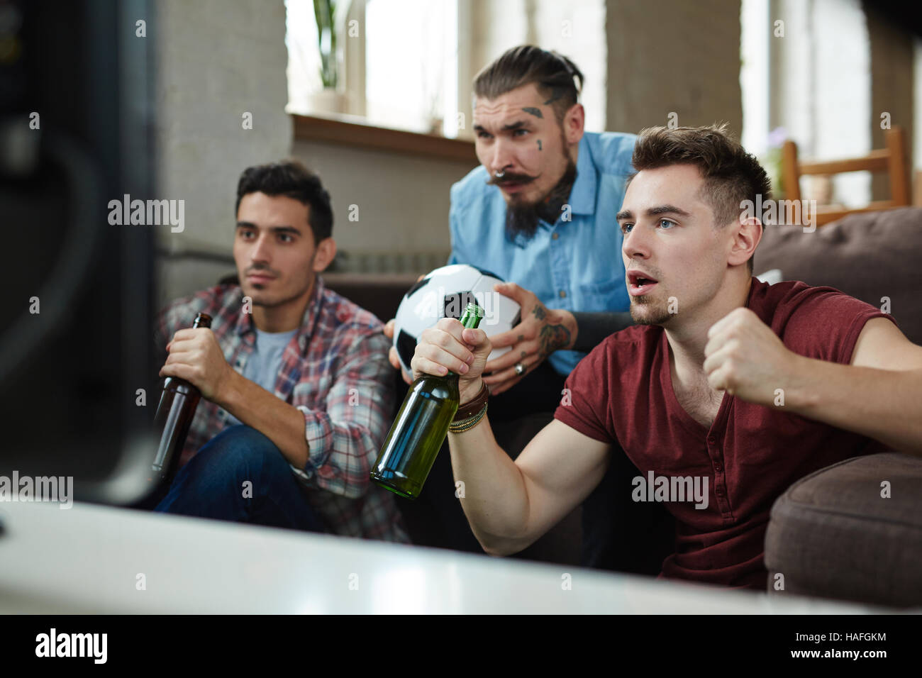 Junge Männer mit Bier nervös beim Fußballspiel im Fernsehen ansehen Stockfoto