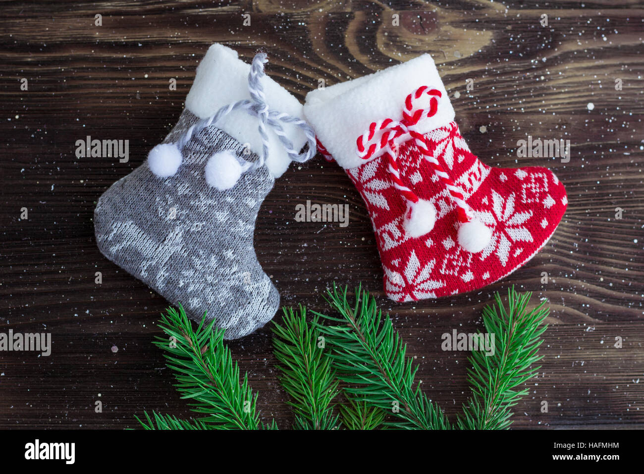 Weihnachten und Neujahr Urlaub Zusammensetzung der grünen Tanne Äste, rot und grau gestrickte Strumpf auf braunem Holz Hintergrund Stockfoto