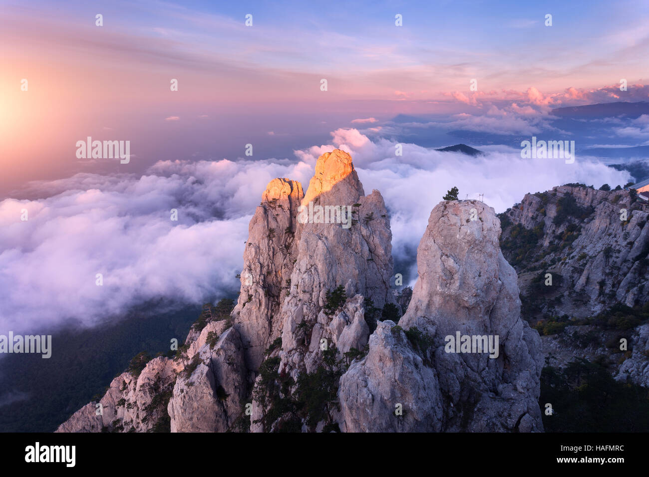 Berglandschaft bei Sonnenuntergang. Blick vom Gipfel auf hohen Felsen, blauer Himmel, Wolken und Meer. Niedrige Wolken Stockfoto