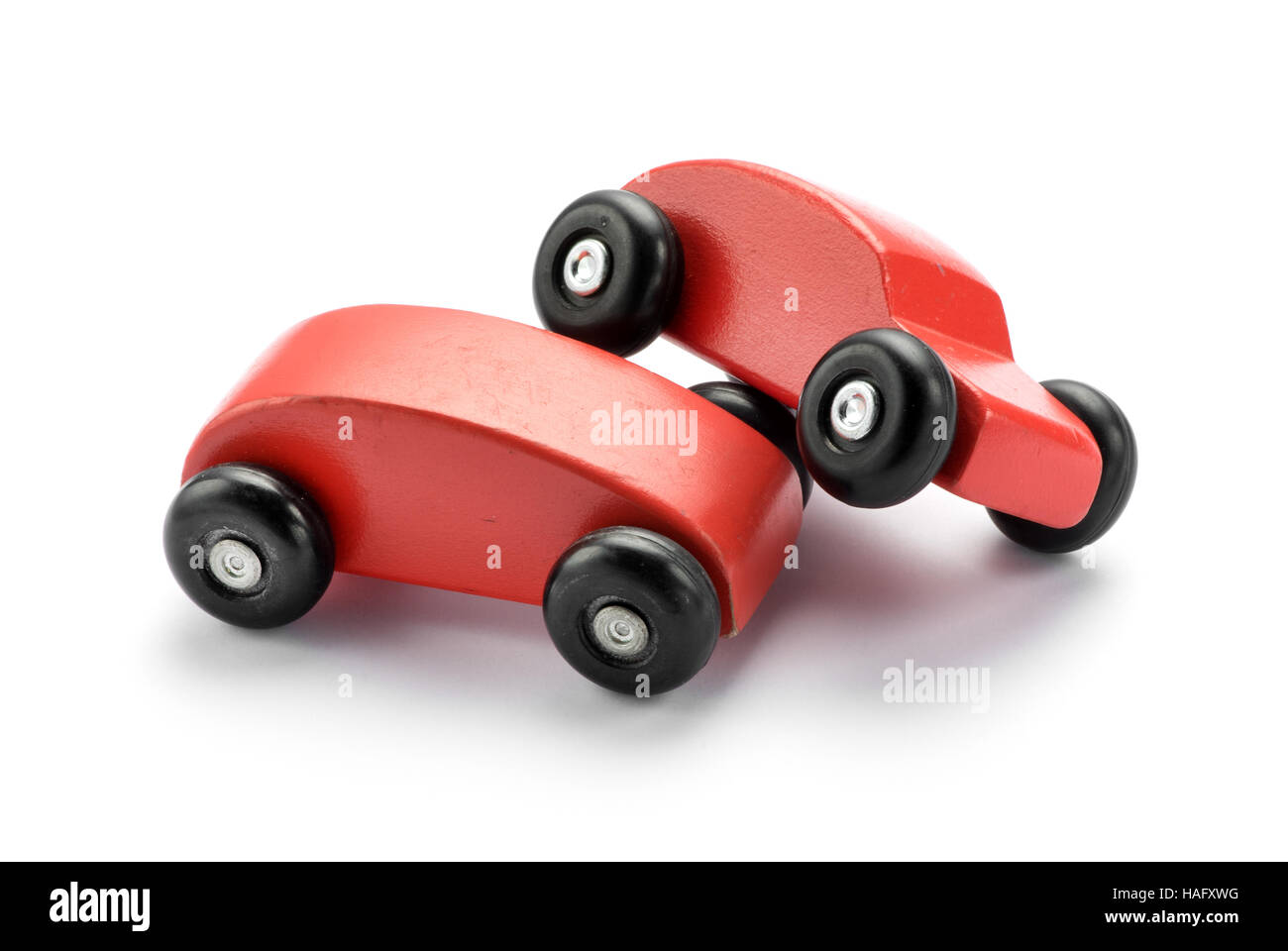 Zwei stilisierte Spielzeug aus Holz rote Autos Stapeln auf einem anderen begrifflichen eines Kraftfahrzeug-Verkehrsunfall oder einer Kollision auf weiß mit Textfreiraum Stockfoto