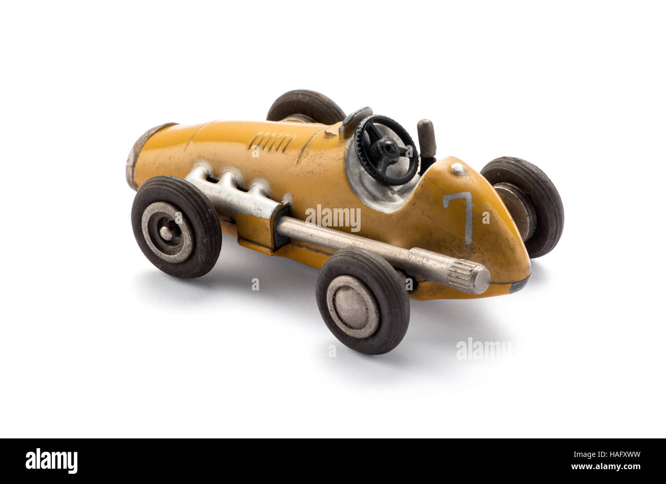 Modell gelb Spielzeug Oldtimer Rennwagen in einer Seitenansicht zeigt den großen Auspuff über einen weißen Hintergrund mit Schatten Stockfoto