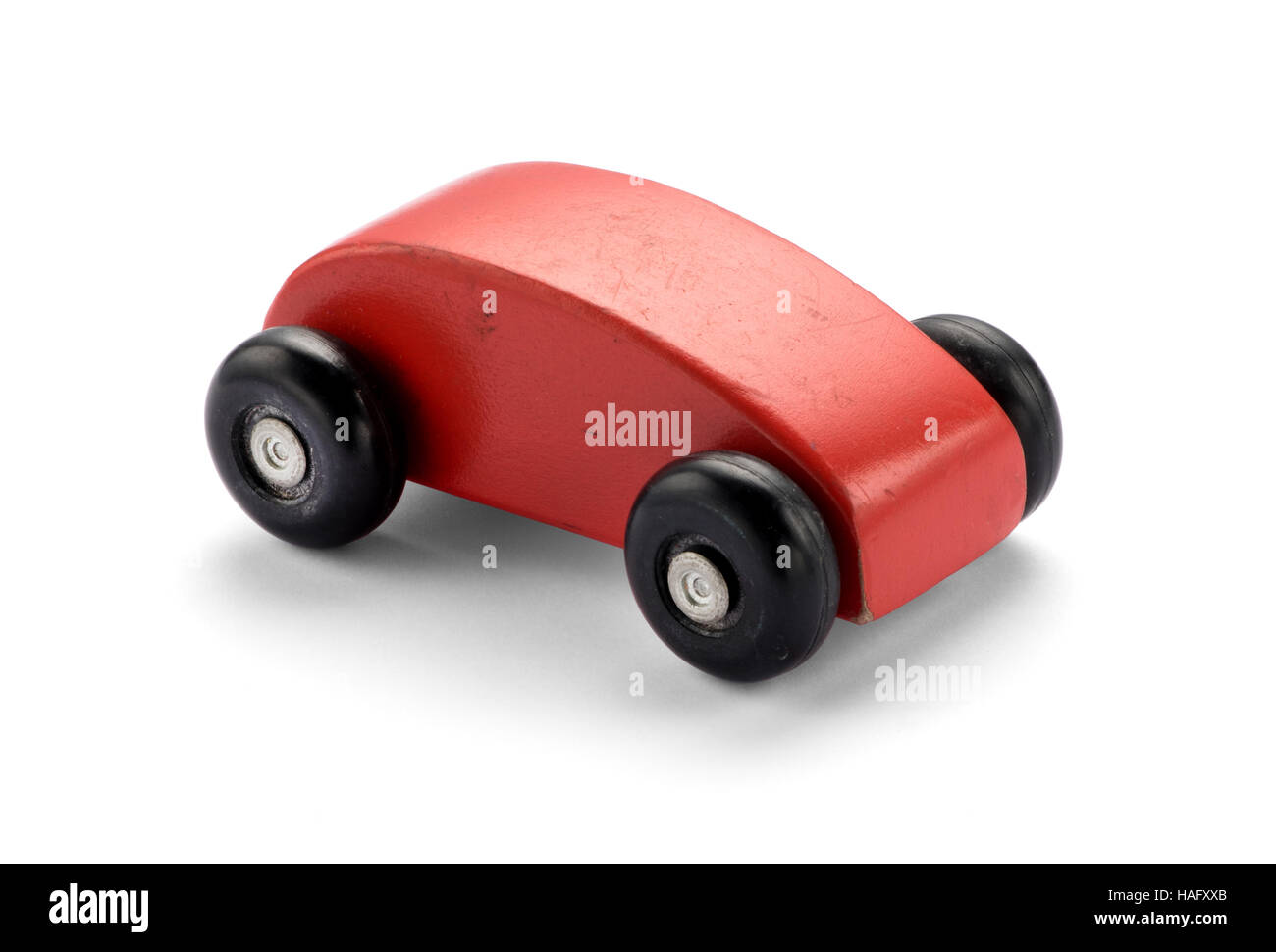 Einfache stilisierte rote hölzernes Spielzeugauto mit einem geschwungenen Design auf großen Rädern in einem hohen Winkel Seitenansicht auf weiß Stockfoto