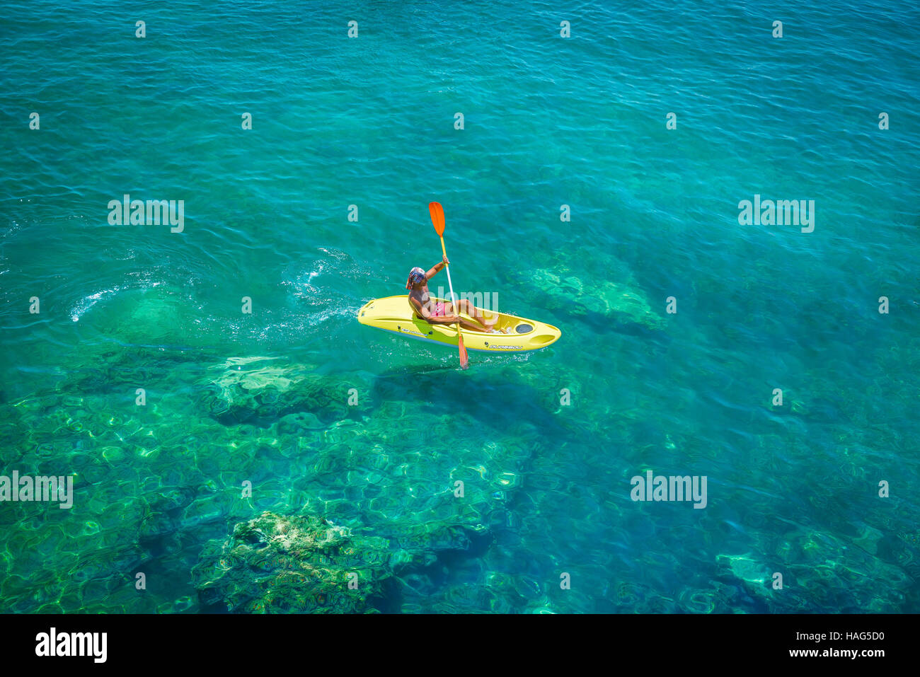 Man Kanu Meer, Blick auf einen Mann paddeln einen kleinen gelben Kanu über den Hafen von Ortigia, Sizilien. Stockfoto