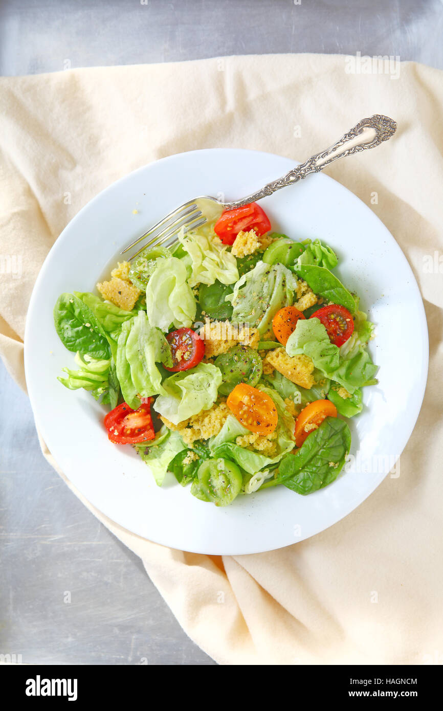 Salat aus Kopfsalat, Baby-Spinat und Kirschtomaten mit zerbröselten Maisbrot Stockfoto