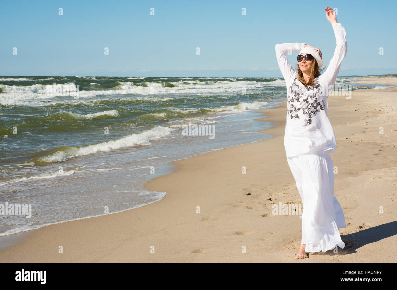 Frau in einem weißen Kleid Spaziergänge am Meer Stockfoto