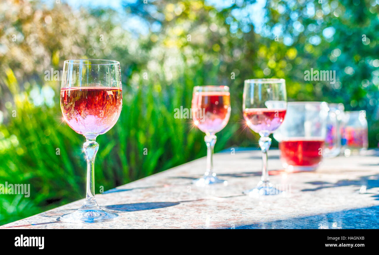 Rosa Wein in Stielgläser auf einem Tisch in einem Garten an einem sonnigen Tag Stockfoto