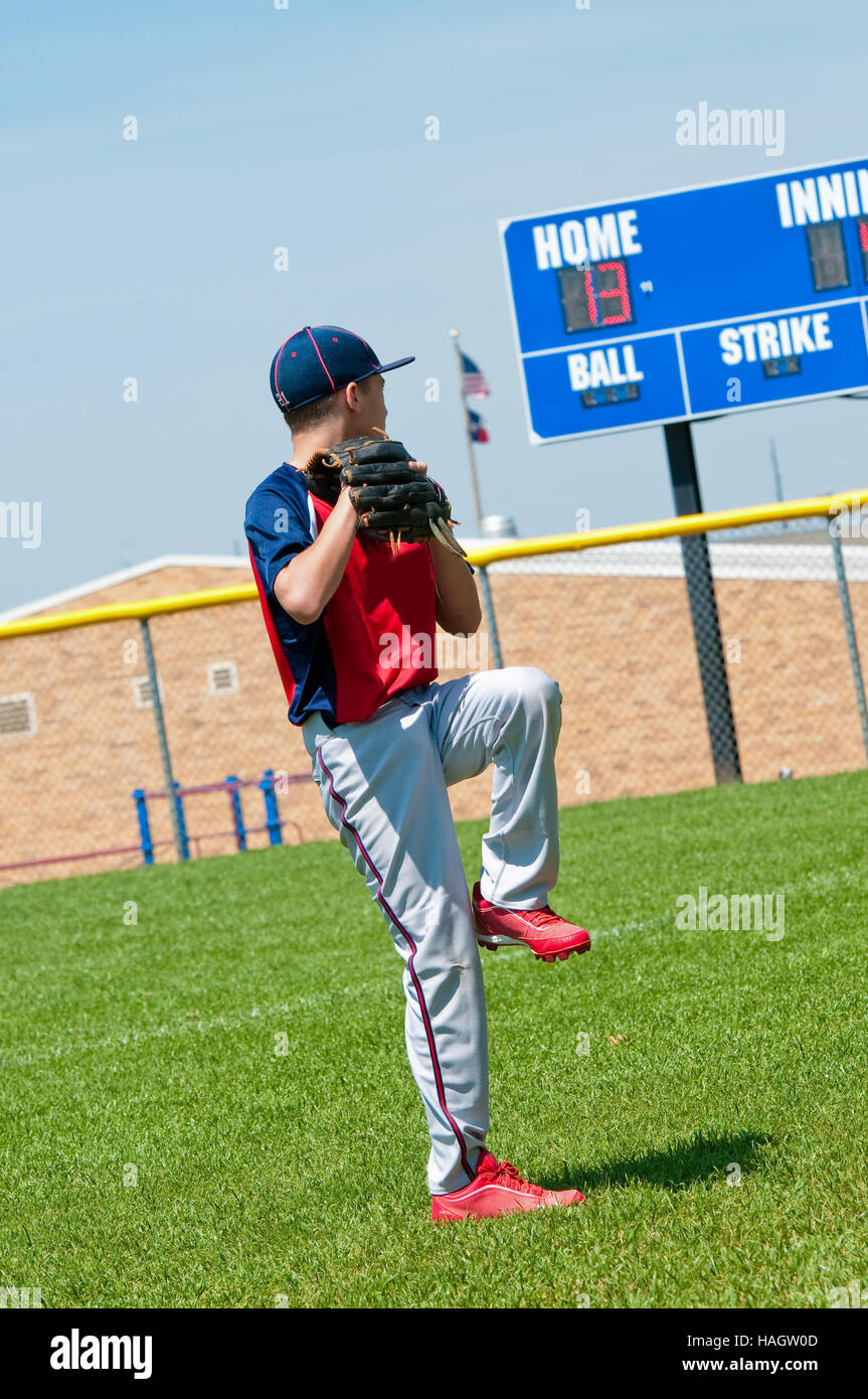 US-amerikanischer Junge pitching mit Anzeigetafel im Hintergrund. Stockfoto