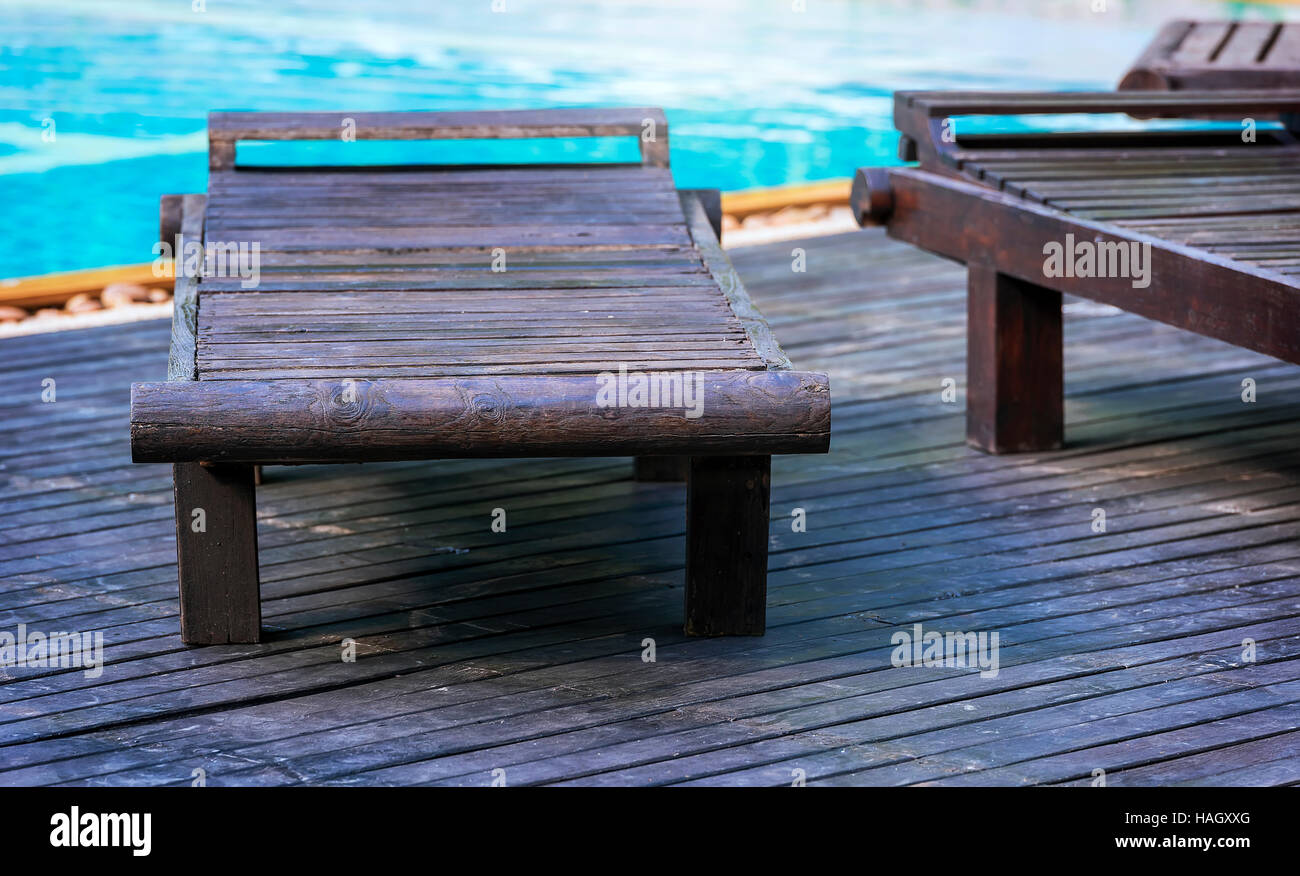 Im Freien am Pool liege Stühle, Holzbänke neben dem Schwimmbad Stockfoto