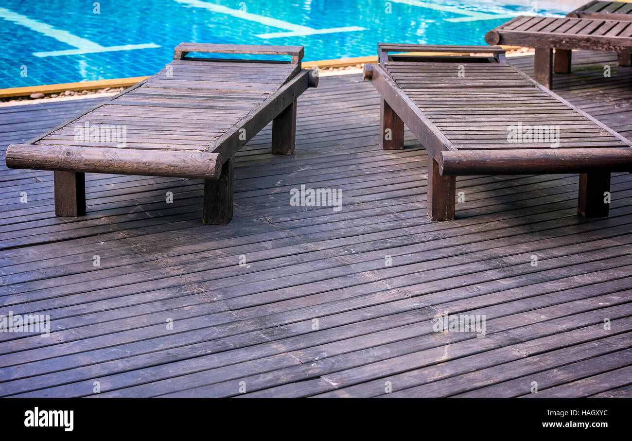 Im Freien am Pool liege Stühle, Holzbänke neben dem Schwimmbad Stockfoto