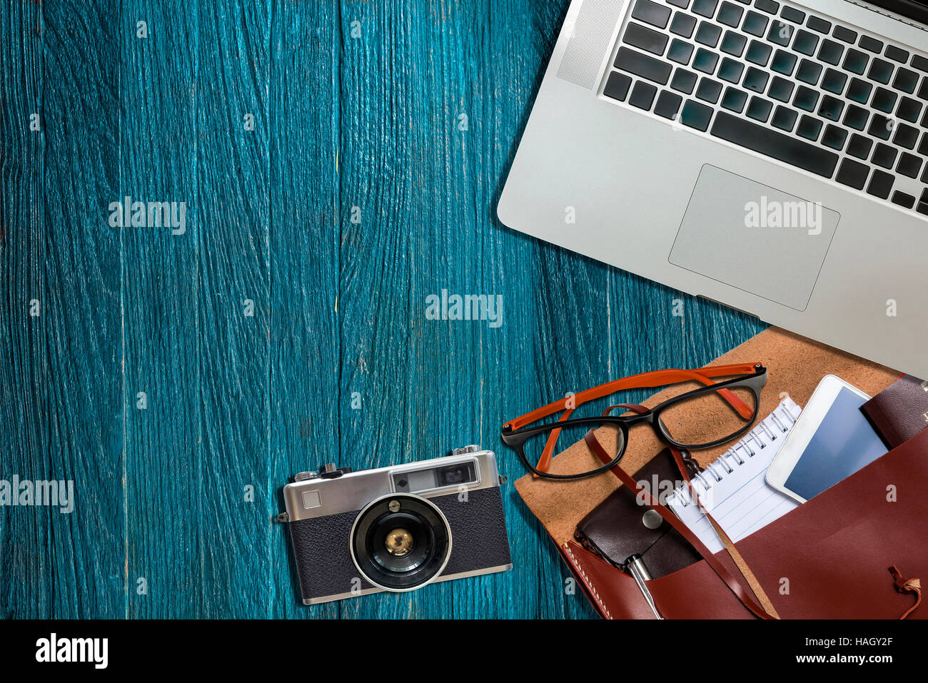 Schreibtisch Büro, Laptop, Kamera, Augen-Brillen, Telefon auf blauem Hintergrund aus Holz. Bereit für die Arbeit Stockfoto