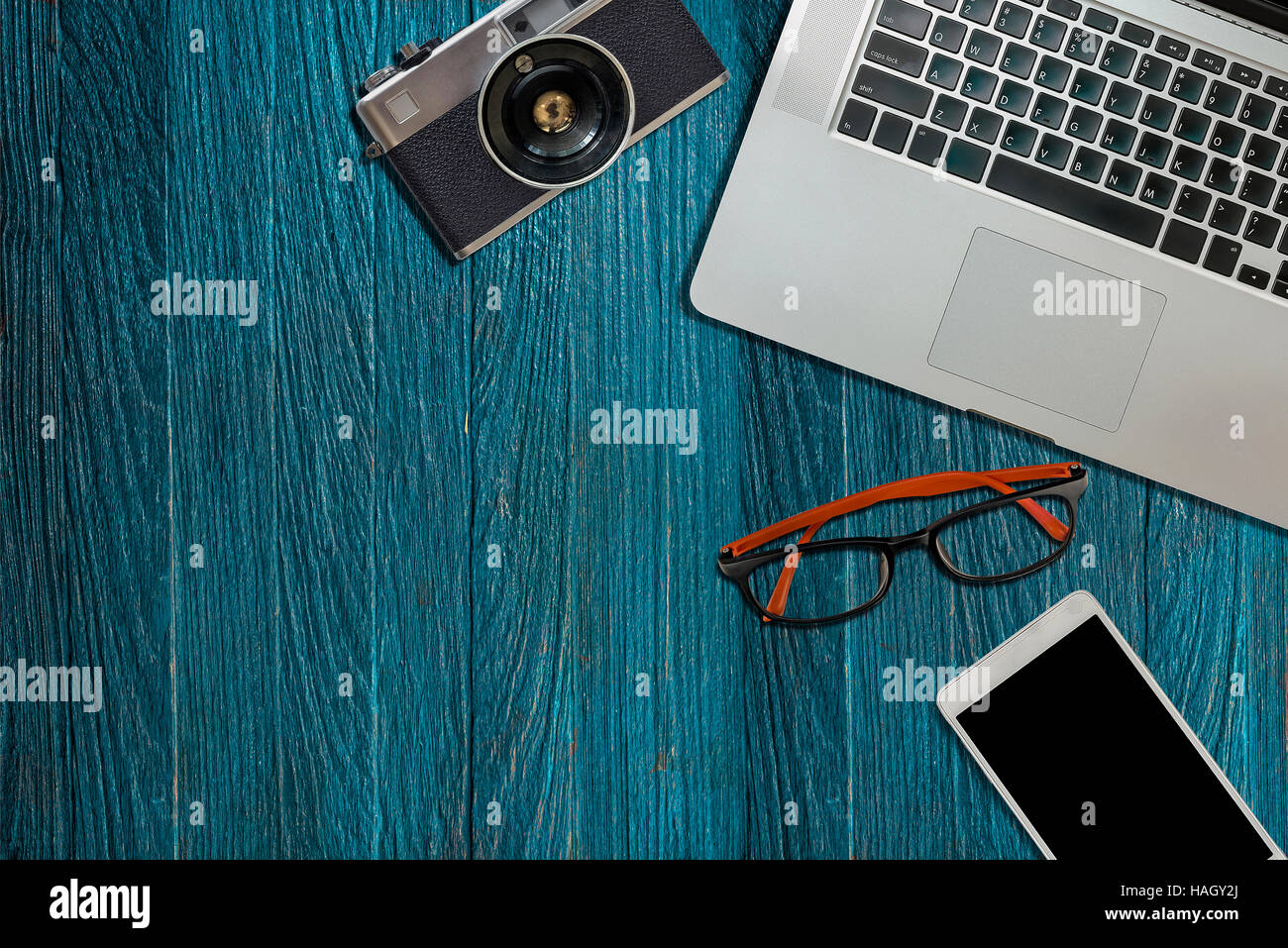 Schreibtisch Büro, Laptop, Kamera, Augen-Brillen, Telefon auf blauem Hintergrund aus Holz. Bereit für die Arbeit Stockfoto