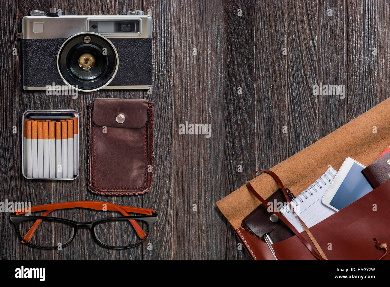 Reise-Zubehör, Kamera, Augen Brille, Handy Tasche, Pass, Zigarette auf schwarzem Hintergrund aus Holz. Bereit für die Reise Stockfoto