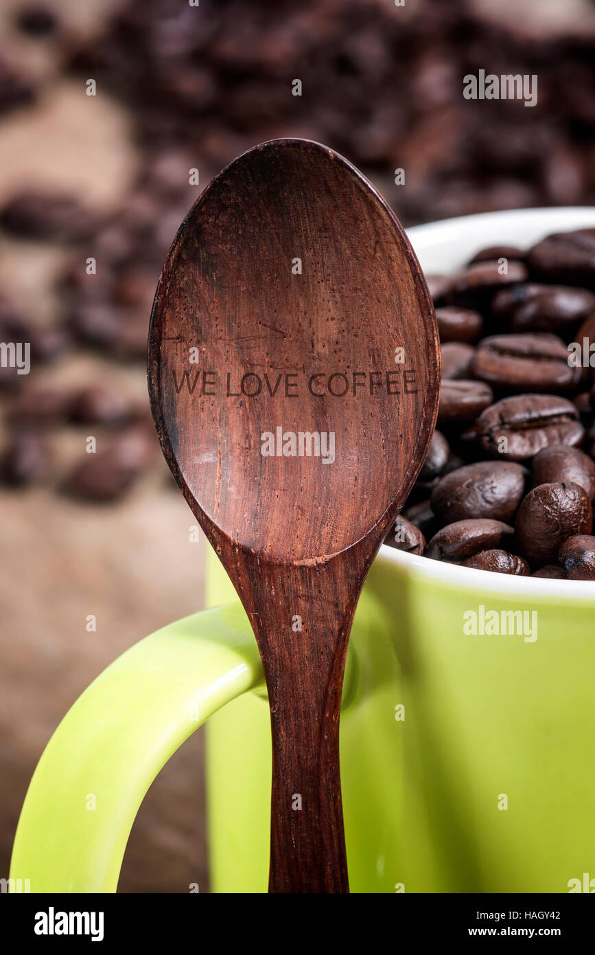 Holzlöffel und grüne Tasse Kaffee Bohnen, Liebe Kaffee-Konzept. Stockfoto